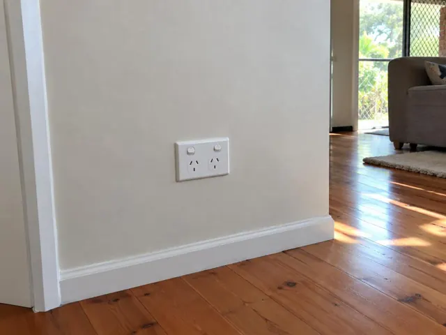 White double power point on a painted wall above timber floorboards in a home interior in Maudsland