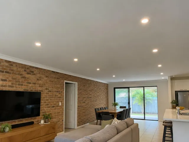 Living room with recessed downlights in a brick and plaster open-plan home interior in Oxenford