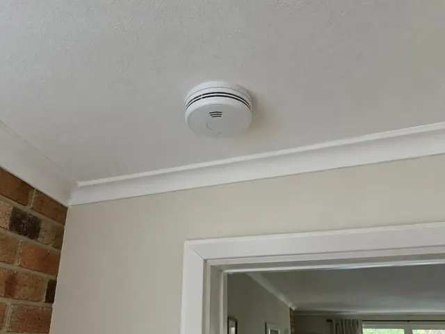 Ceiling-mounted smoke alarm above a cream wall and doorway in a home interior in Pacific Pines